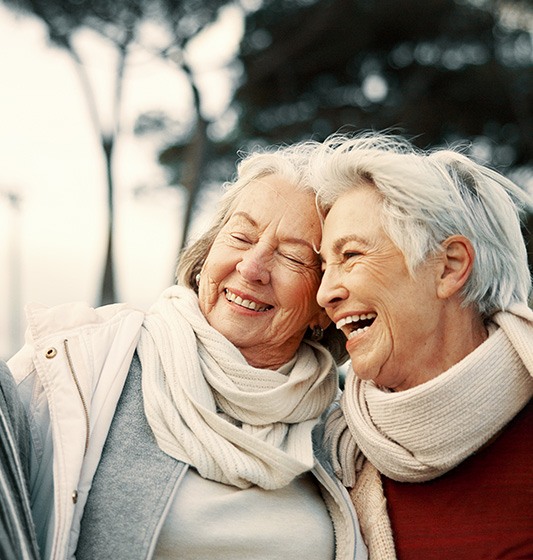 Three women with scarves outside laughing