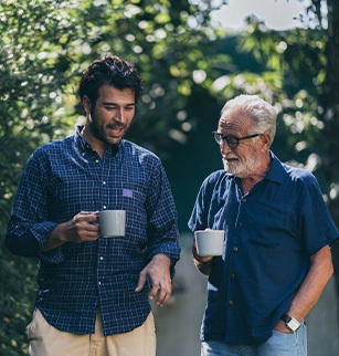 Two men outside talking over a cup of coffee