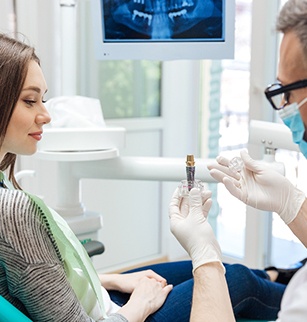 A male dentist showing his female patient a dental implant