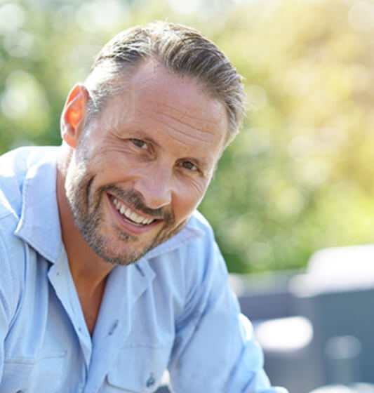 a man smiling and sitting in a park